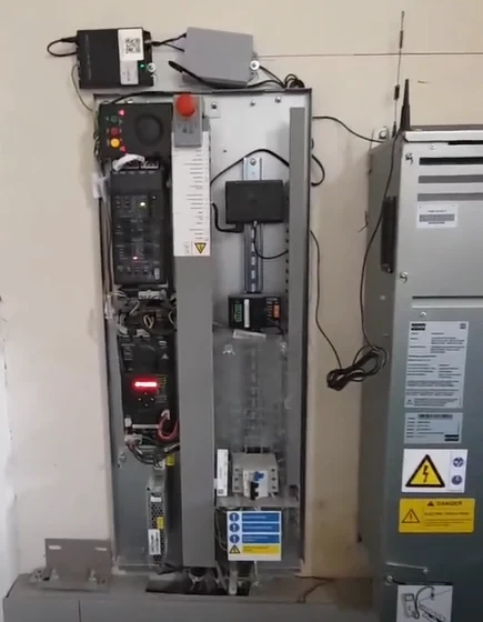 technician inspecting elevator control cabinet in machine room